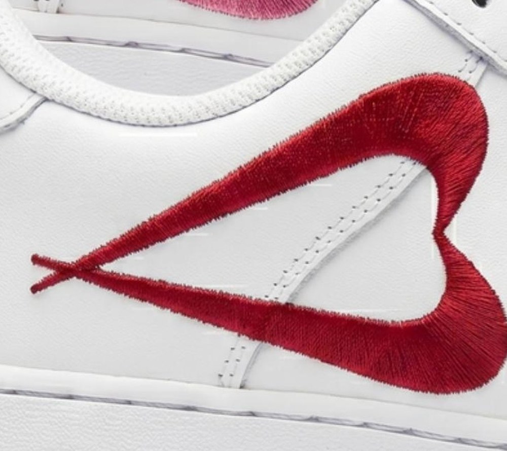 Close-up of two mirrored Nike Swooshes stitched as a dense satin-stitch fill, forming a heart on the toe of an Air Force 1